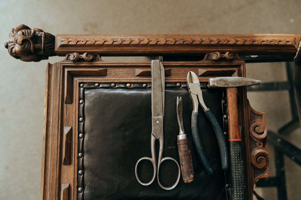 A collection of vintage tools on an antique wooden chair with ornate carvings, showcasing a retro workshop vibe.